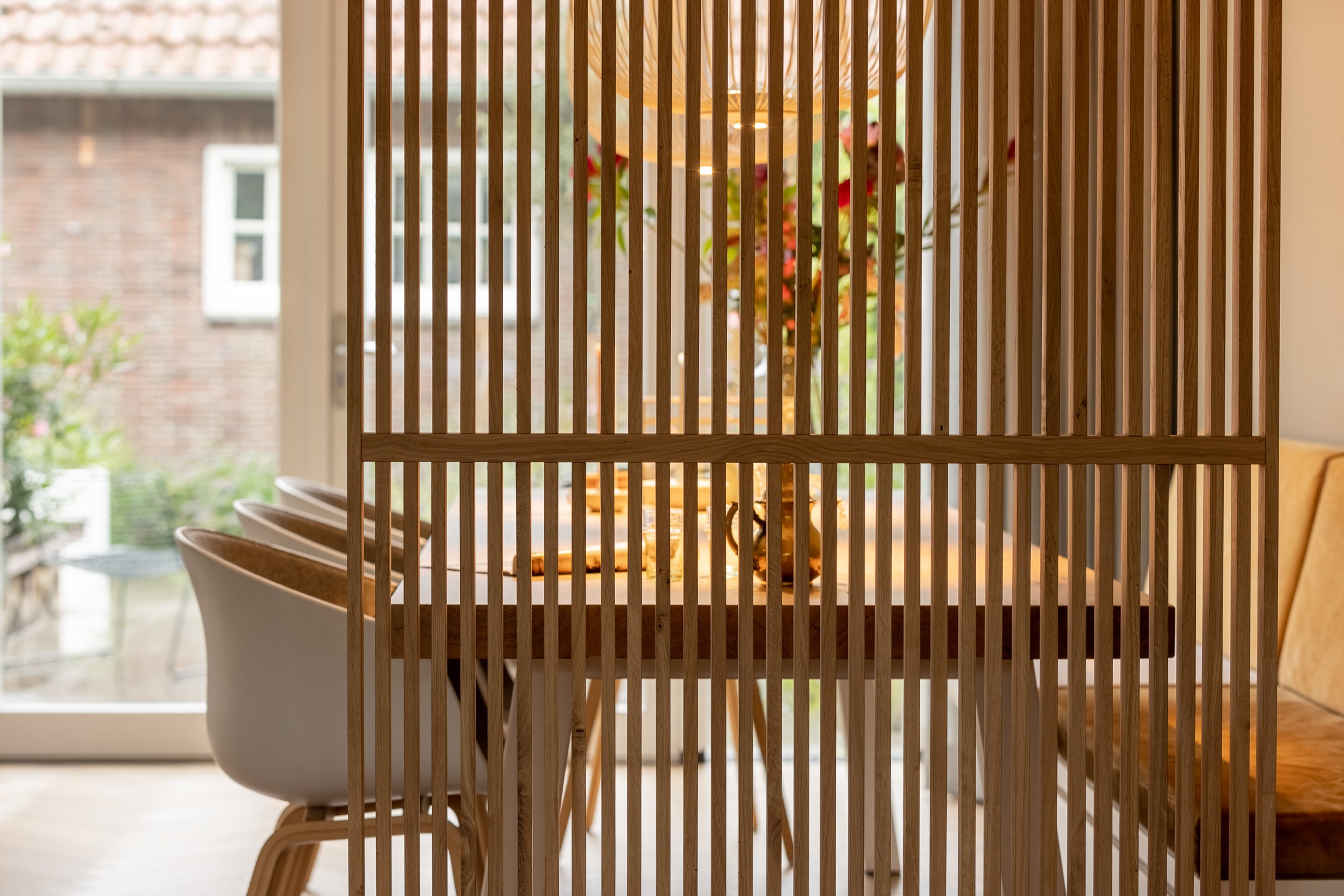 Houten roomdivider tussen woonkamer en eettafel in een smalle lange woonkamer