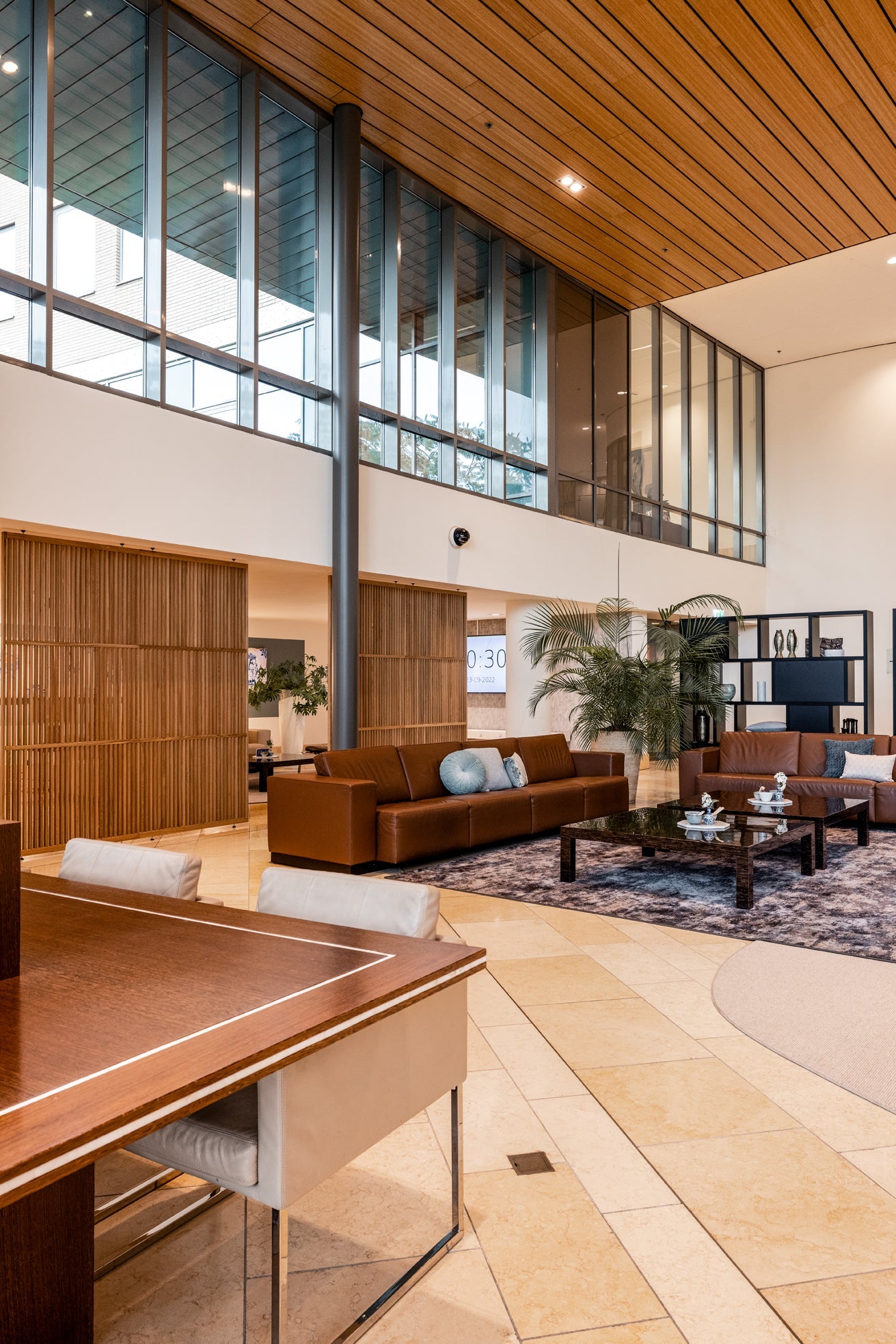 Houten roomdividers scheiden subtiel een groot kantoor, waardoor een duidelijke indeling ontstaat in de ontvangst- en receptieruimte van het kantoor.