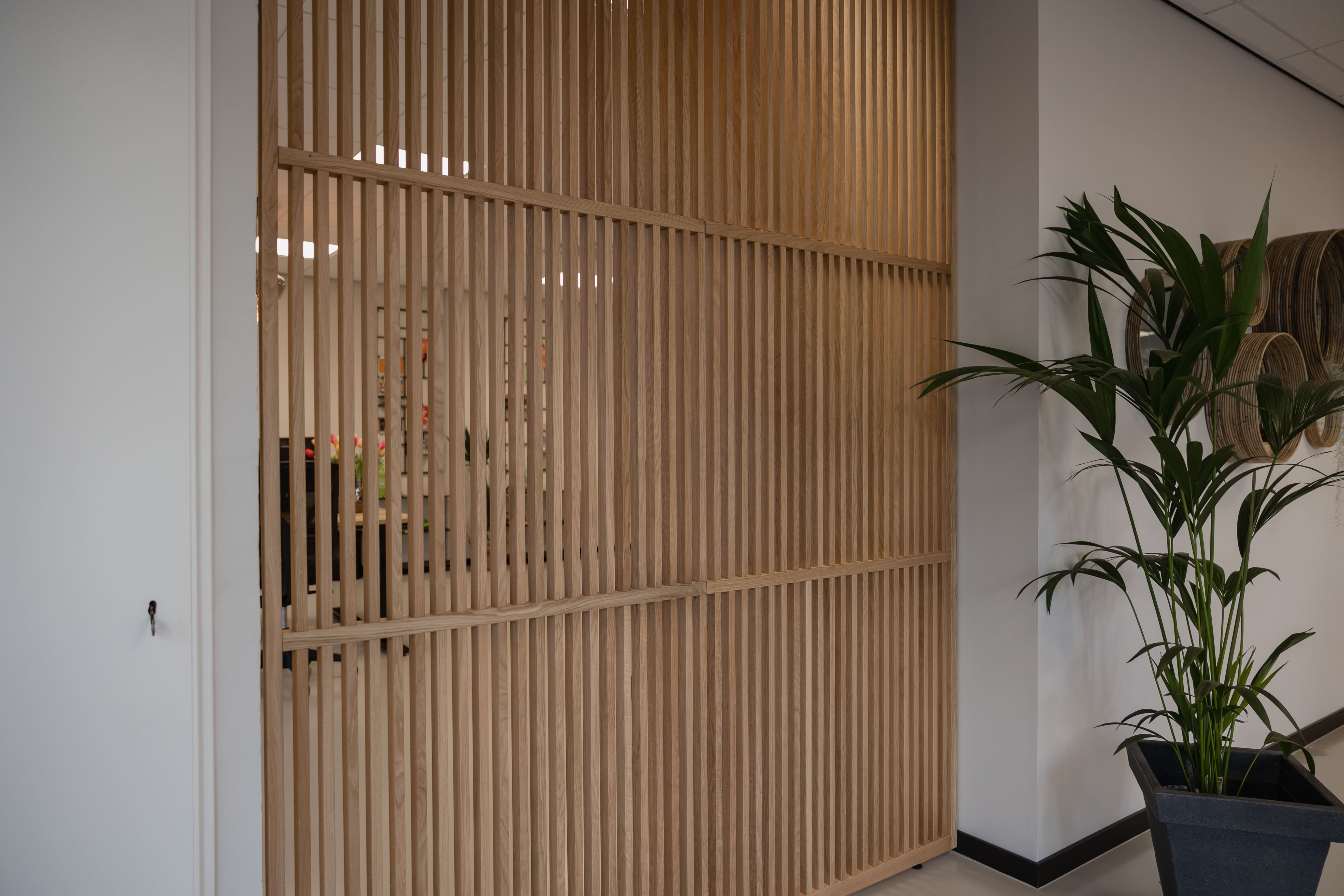 XL houten scheidingswand in een kantoor zorgt voor een elegante verdeling van werkruimtes, biedt privacy en behoudt een open, lichte sfeer in de ruimte.