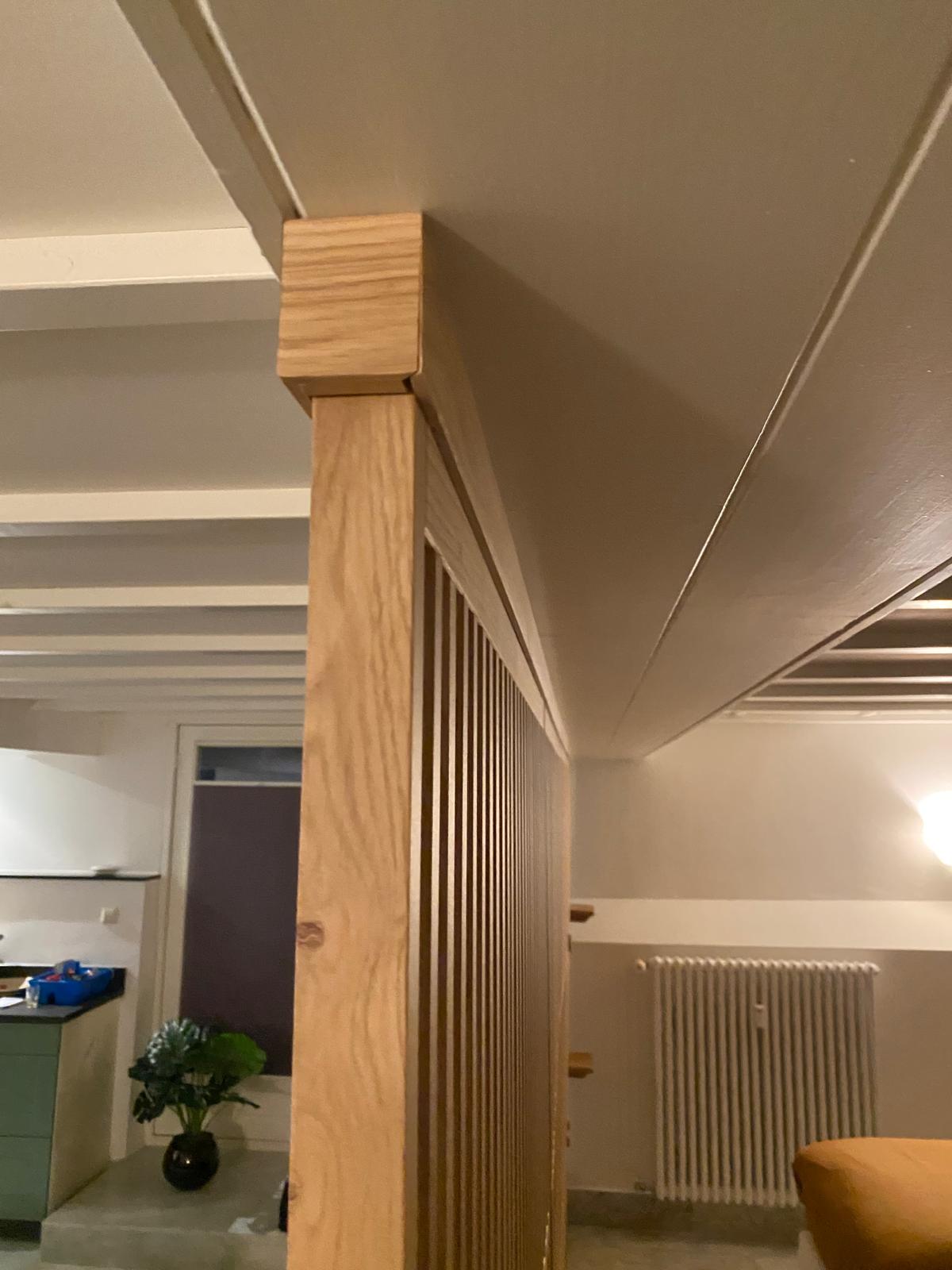 Detailfoto van een massief eiken roomdivider tot aan het plafond met strakke plafondmontage en verticale houten latten
