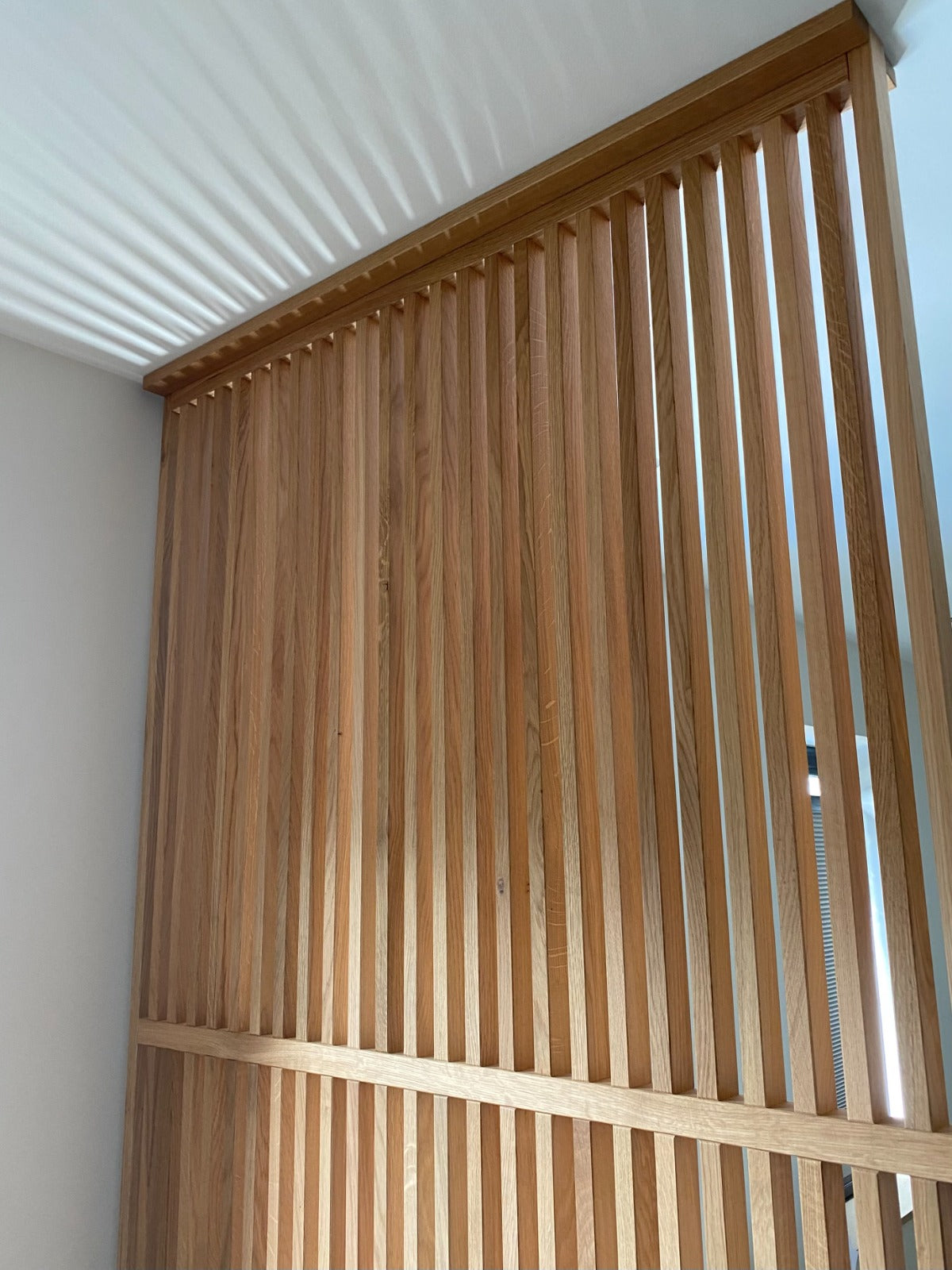 Houten roomdivider gemonteerd met montagelatten tegen het plafond