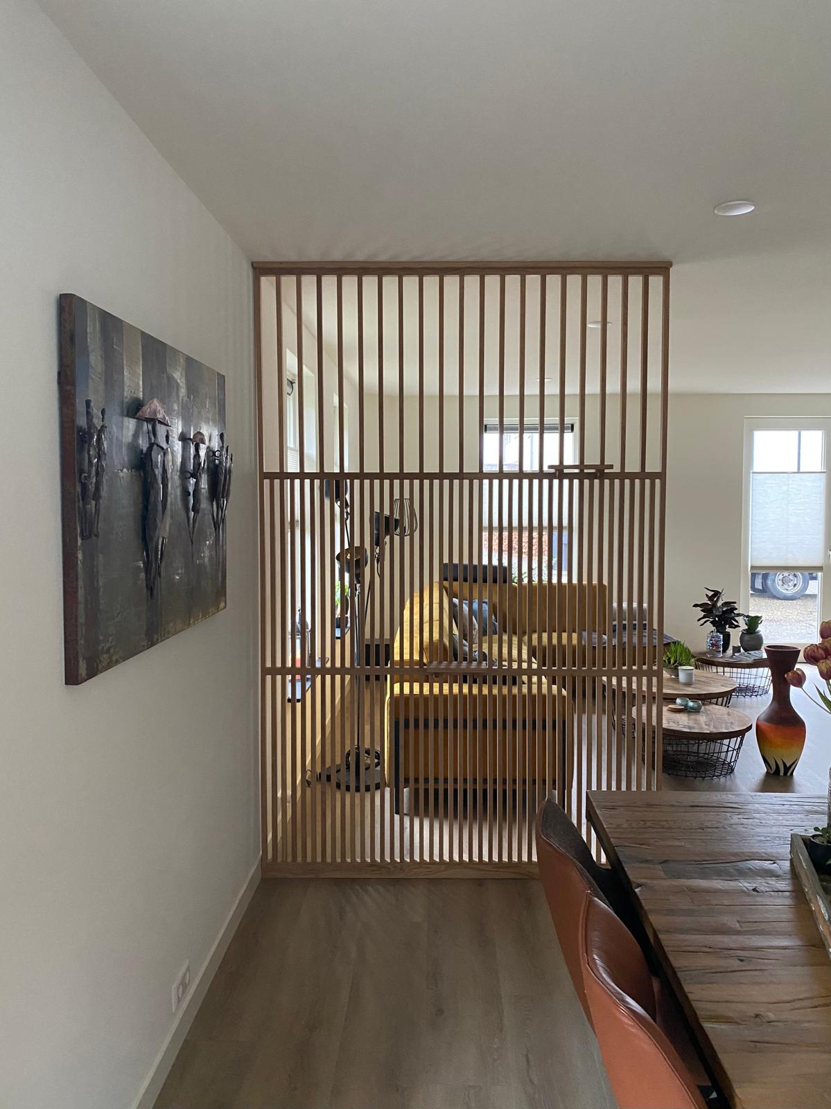 Minimalistische zwarte roomdivider Model Light® op maat. Creëert een transparante afscheiding tussen eettafel en zithoek met behoud van licht. Voorbeeld getoond in eiken uitvoering.