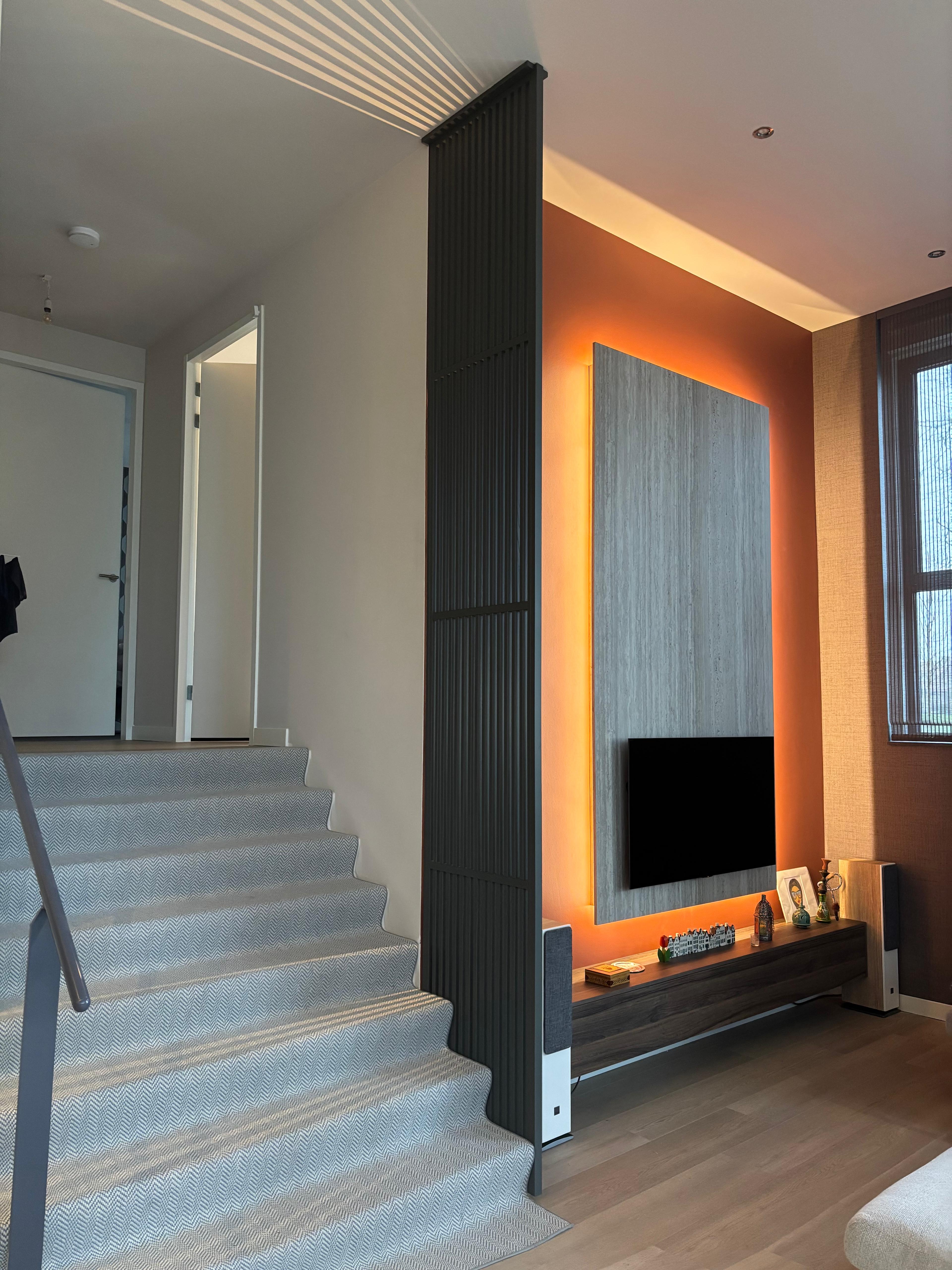 Zwarte plafondhoge roomdivider in woning met extra hoog plafond en moderne trapopgang